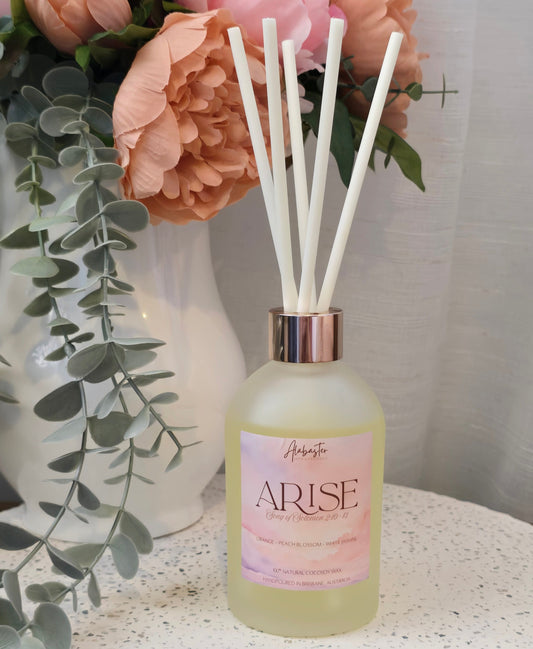 Diffuser bottle labeled 'ARISE' with reeds and flowers on a textured surface